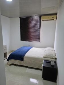 a bedroom with a bed with a window and a table at El apartacho de Andres in Valledupar