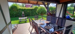 a table and chairs on a patio with a bottle of wine at Dabki Village - Villa Rena in Dąbki