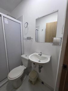 a white bathroom with a toilet and a sink at El apartacho de Andres in Valledupar