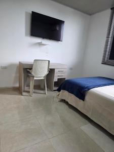 a bedroom with a bed and a desk and a television at El apartacho de Andres in Valledupar