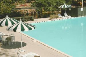 a swimming pool with two umbrellas and chairs next to it at Petit Cowboy in New Braunfels +14 photos