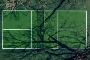 a tennis court with a shadow of a tree at Petit Cowboy in New Braunfels