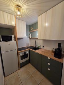 a kitchen with green cabinets and a white refrigerator at Eden lodge Chessy - 10min Disneyland - Parking in Chessy