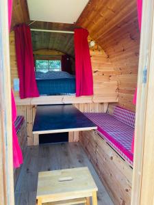 a inside of a wooden cabin with a bed and red curtains at Barrel Cabin 2 in Trethurgy +6 photos