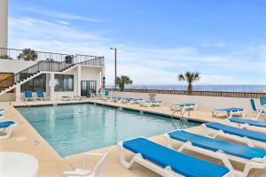 a swimming pool with lounge chairs and the ocean at Amazing Oceanfront Home HS 4th Floor in Myrtle Beach