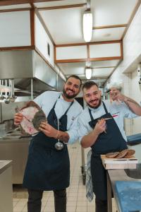 Drei Männer in einer Küche, die einen Teller mit Essen halten in der Unterkunft Hotel Casa56 in Weiswampach