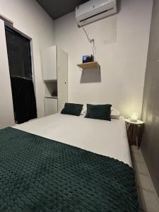 a bedroom with a large white bed with two green pillows at Suíte Neblina in Garanhuns +8 photos