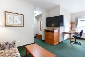 a hotel room with a desk and a flat screen tv at Lakeview Inns & Suites - Okotoks in Okotoks
