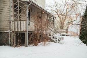 a house with a staircase in the snow at Rozā Dāvids in Liepāja