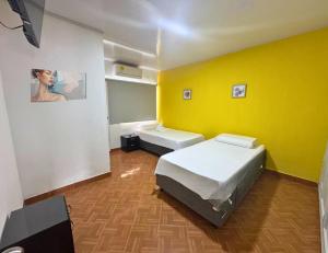 a room with two beds and a yellow wall at Hotel Casa Manzanares in Santa Marta