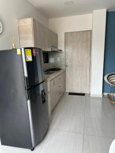 a kitchen with a stainless steel refrigerator and wooden cabinets at Apartaestudio amoblado 303 Edificio Buenos Aires Sincelejo in Sincelejo +4 photos