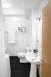 a white bathroom with a toilet and a sink at Apartman Lori M sa parkingom in Kraljevo +11 photos