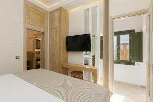 a bedroom with a bed and a flat screen tv at Ocean Caldera View Villa by Dalmyra Estate in Imerovigli