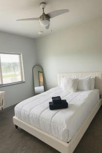 a bedroom with a white bed with a ceiling fan at Blackbeam Suite in Des Moines