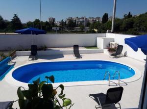 a large swimming pool with chairs and umbrellas at Holiday House Franov in Zadar