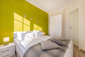 a bedroom with a large white bed with a green wall at Fewo Kleine Auszeit 02 in Koserow