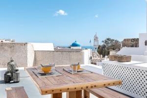 a wooden table on a balcony with drinks on it at Casa Grande Santorini in Megalochori
