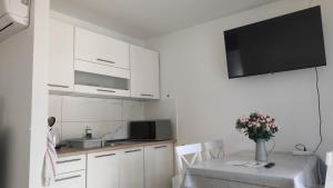 a kitchen with white cabinets and a table with a vase of flowers at Villa Vanília in Keszthely +39 photos