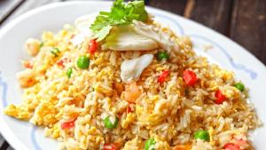 a white plate of rice with chicken and vegetables at A'Resta Samasta Green Lodge in Praya