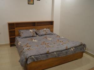 a bedroom with a bed with a wooden headboard at Ananta 1BHK in Birbhaddar