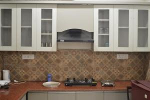 a kitchen with white cabinets and a stove top oven at Ananta 1BHK in Birbhaddar +29 photos
