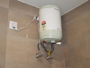 a water tank is attached to the wall of a bathroom at Ananta 1BHK in Birbhaddar