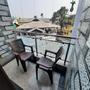 two chairs and a table on a balcony with a boat at Surakha INN LLP in Siliguri
