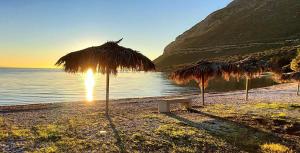a beach with some straw umbrellas and the water at Rizaki Cottage in Nafpaktos in Nafpaktos +35 photos