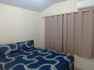 a bedroom with a bed with a blue comforter and curtains at Recanto do Garças in Aragarças