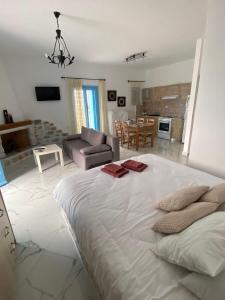 a bedroom with a large white bed and a living room at Yulie's Orama in Areopoli
