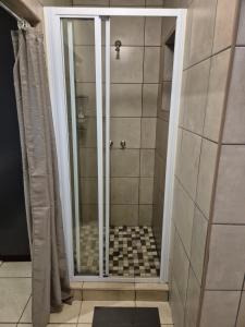 a shower with a glass door in a bathroom at Wattlewood Cabins in Piet Retief +16 photos
