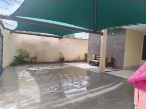 an empty patio with a large green umbrella at Paraíso do aconchego in Aparecida de Goiânia