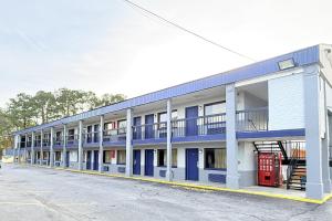 an apartment building with blue doors and a parking lot at OYO Hotel Williamston in Williamston