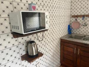 a microwave on a shelf in a kitchen at Résidence Le Petit Manoir in Cotonou
