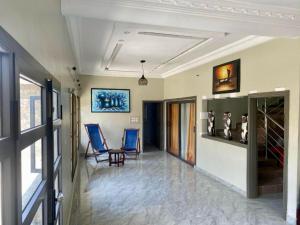 a hallway with two chairs and a painting on the wall at Résidence Le Petit Manoir in Cotonou