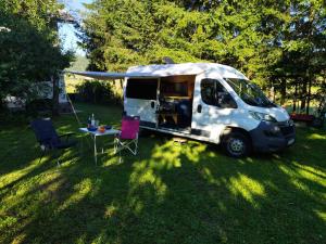 a white van parked in the grass with a table at Kampervan in Vrhovine
