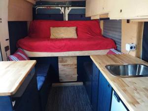 a small room with a bed and a sink in it at Kampervan in Vrhovine