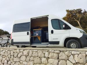 a white van parked next to a stone wall at Kampervan in Vrhovine