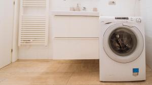 a washing machine in a white laundry room with a sink at XX Settembre 68 in Alassio