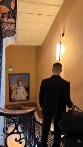 a man standing in a room holding a suitcase at Boutique Hôtel Le Clos Huguerie - Bordeaux Centre in Bordeaux