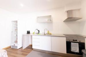 a white kitchen with a sink and a stove at Trajadinha do Lima Rooms in Ponte de Lima
