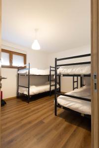 three bunk beds in a room with wooden floors at Trajadinha do Lima Rooms in Ponte de Lima
