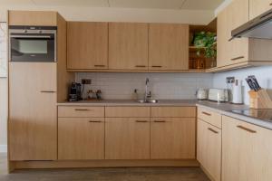 a kitchen with wooden cabinets and a sink at Casa Amare in Egmond aan Zee +21 photos