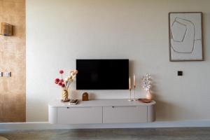 a living room with a tv on a white cabinet at Casa Amare in Egmond aan Zee