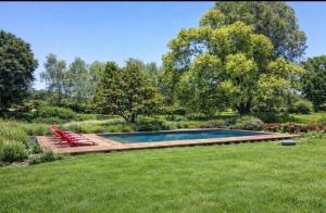 a swimming pool with two red chairs in the grass at Les 3 Roses in Anjouin