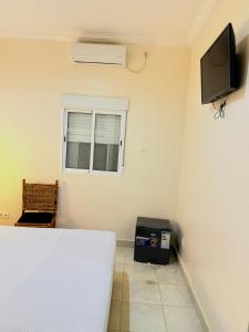 a bedroom with a bed and a tv on the wall at MAG Palace Hotel in Bissau