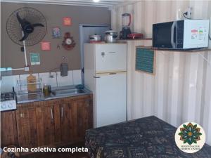a kitchen with a refrigerator and a sink and a microwave at Hospedagem Tribos Livres in Torres