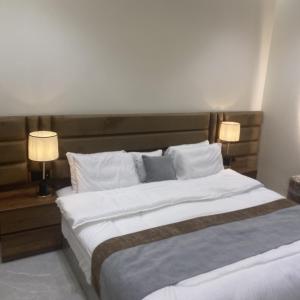 a bedroom with a large bed with two lamps at مسكن ترف للشقق الفندقية in Al Majma'ah