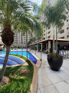 a courtyard with palm trees and a swimming pool at Privê Boulevard Suíte Hotel - 706 - Caldas Novas GO in Caldas Novas