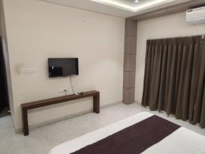 a room with a flat screen tv on a wall at Hotel Bhasmaarti Ujjain in Ujjain